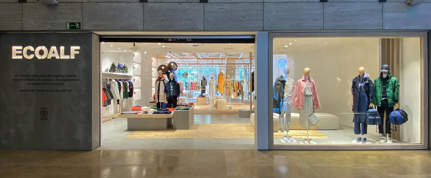 Escaparate de tienda Ecoalf con maniquíes vestidos con abrigos y chaquetas de pluma reciclada.