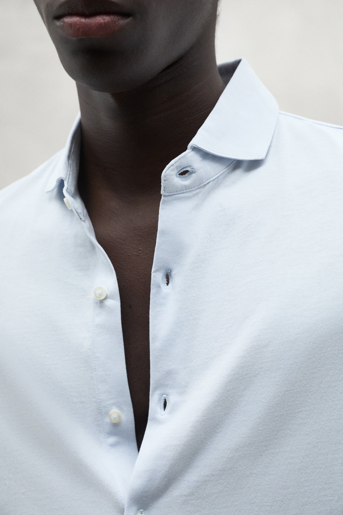 Detalle de cuello y botones de camisa blanca de la marca Ecoalf confeccionada con tejidos sostenibles.