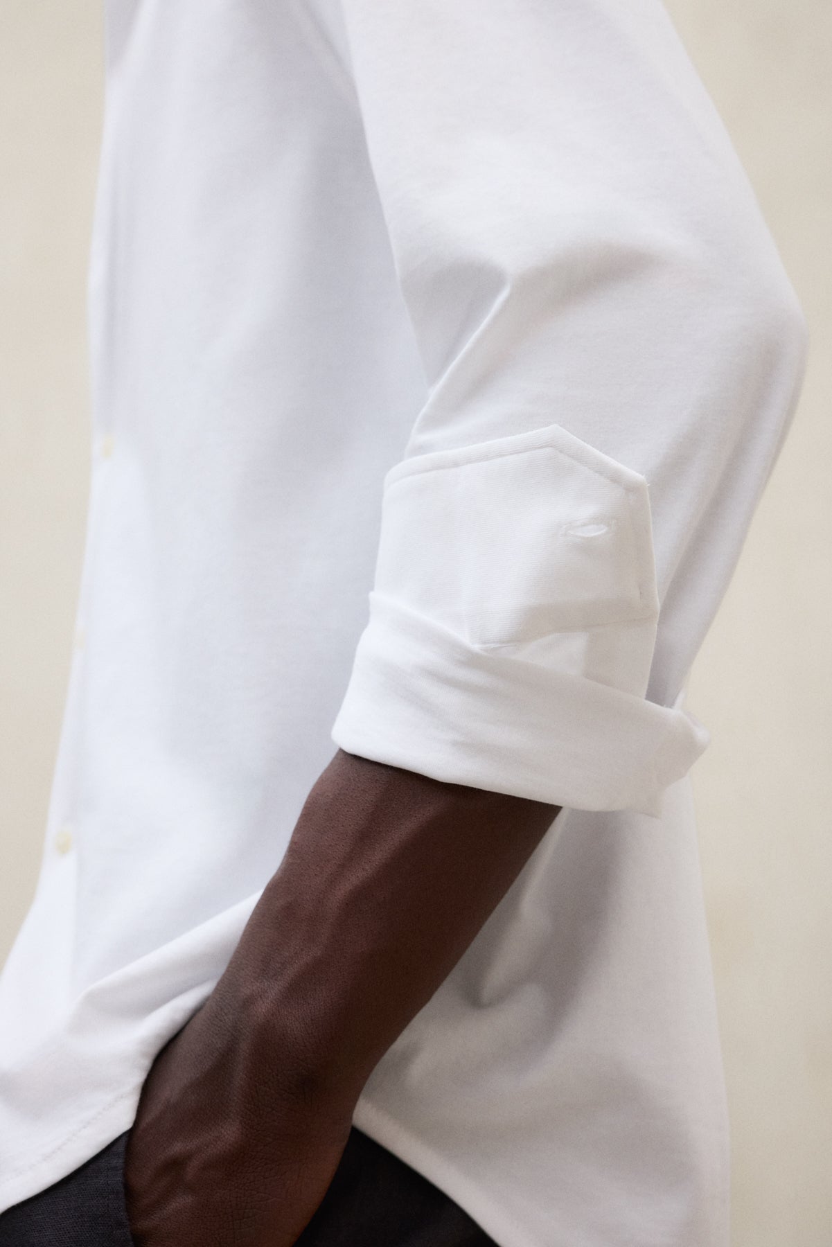 Primer plano de una camisa de Ecoalf blanca con las mangas remangadas, con el antebrazo a la vista.