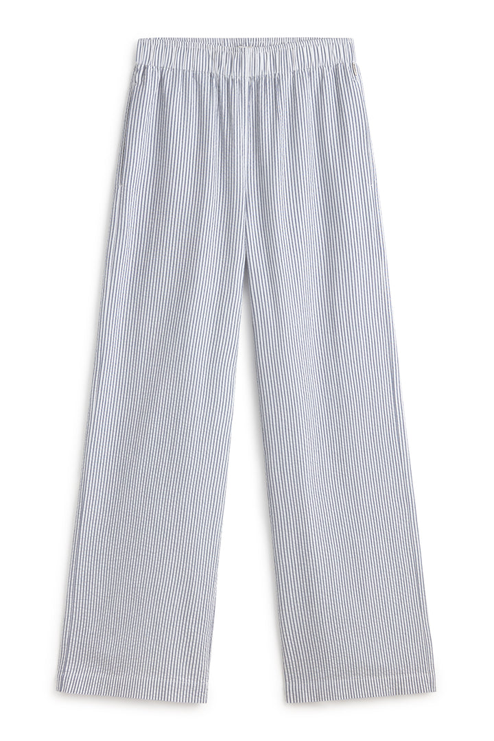 Un pantalón de pijama de Ecoalf sostenible a rayas verticales azul y blanco, de cintura elástica y corte amplio.
