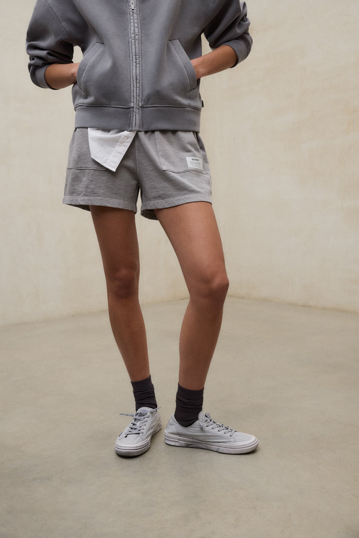 Shorts grises sostenibles de la marca ecoalf.livebinados con zapatillas blancas y calcetines oscuros para un estilo casual.