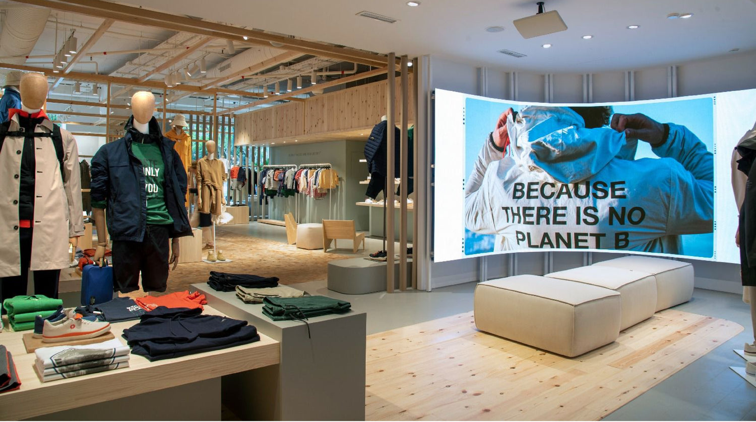 Espacio de la marca Ecoalf con maniquíes vestidos con ropa sostenible y una gran pantalla mostrando un mensaje ambiental.